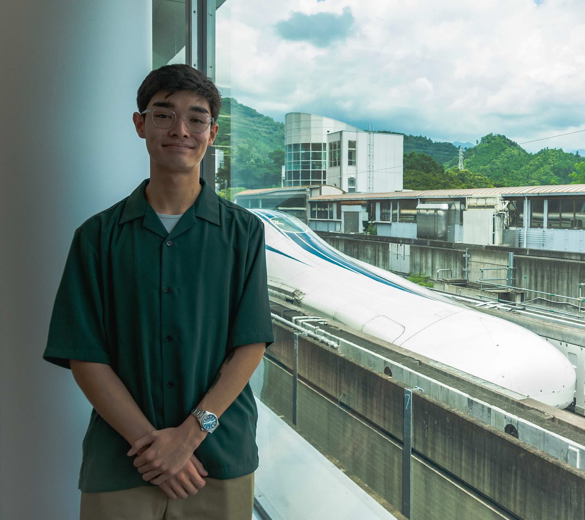 Kai Toppa standing in front of the SCMAGLEV train on its track near Tokyo